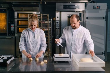 İki fırıncı hamur işini pişirmeden önce şekillendirir, keser ve profesyonel pasta imalatına sunar.