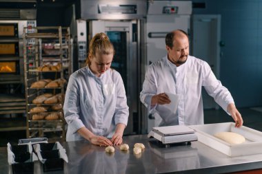 İki fırıncı hamur işini pişirmeden önce şekillendirir, keser ve profesyonel pasta imalatına sunar.