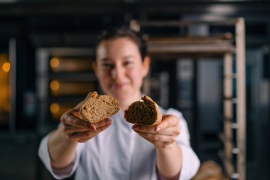 Fırıncı taze pişmiş çıtır çıtır ekmekli çörek fırını prodüksiyon uzmanı mutfağı gösteriyor.