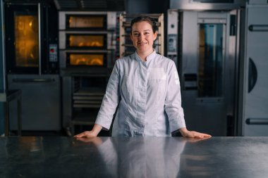 Üniformalı güzel kadın fırıncı işe başlamadan önce fırının yanında duruyor.