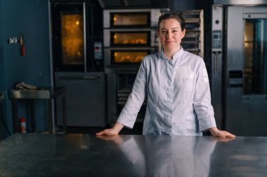 Üniformalı güzel kadın fırıncı işe başlamadan önce fırının yanında duruyor.