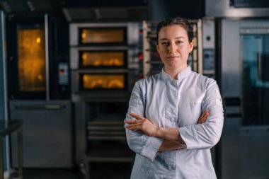 Üniformalı güzel kadın fırıncı işe başlamadan önce fırının yanında duruyor.