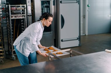 Çekici fırıncı masaya yeni pişmiş sıcak kokulu çöreklerle birlikte bir fırın örtüsü koyar.