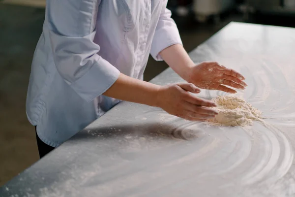 一位经验丰富的厨师在一家面包店做面包之前 先把面粉涂在手上 然后再在专业厨房里准备糕点 — 图库照片