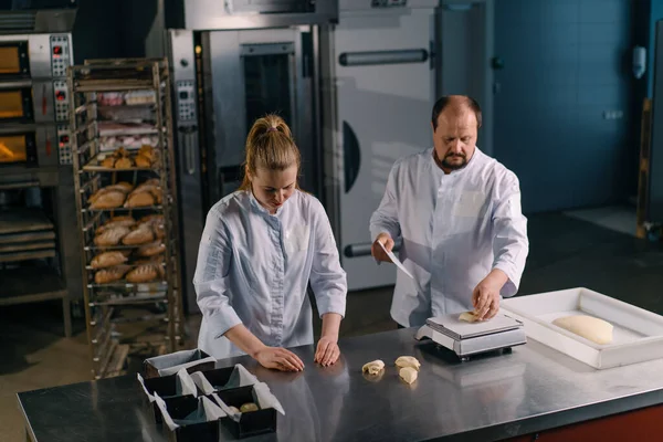 İki fırıncı hamur işini pişirmeden önce şekillendirir, keser ve profesyonel pasta imalatına sunar.