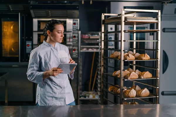 Una Mujer Panadero Uniforme Cerca Los Estantes Con Pan Recién — Foto de Stock