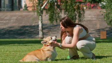 Genç bir kızın portresi ve şirin bir Corgi köpeği. Sahibi parkta yürürken köpeği burnundan öper.