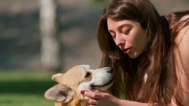 Genç bir kızın portresi ve şirin bir Corgi köpeği. Sahibi parkta yürürken köpeği burnundan öper.