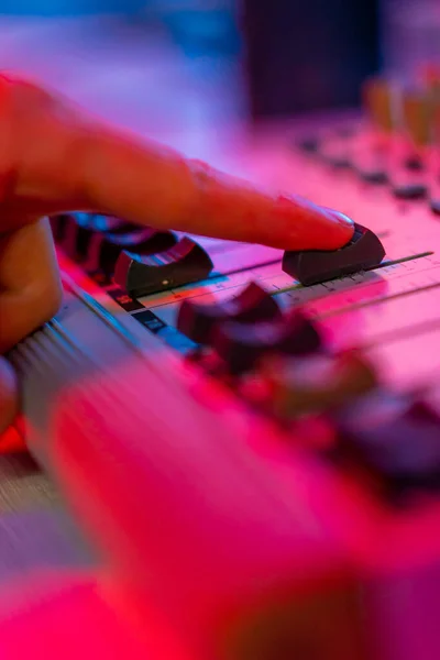 专业录音室音响工程师手指调整音量级混音器控制台均衡器音乐创作霓虹灯 — 图库照片