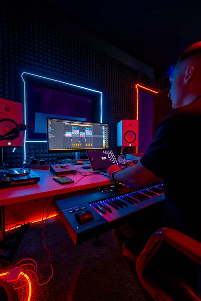 スクリーンネオンライトのリモコンミキシングトラックに座っているプロのサウンドレコーディングスタジオサウンドエンジニアまたは音楽プロデューサー — ストック写真