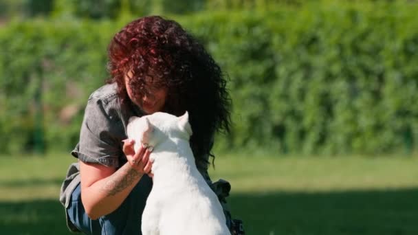 Красивая Кудрявая Девушка Целует Нос Белой Собаки Большой Породы Питбуля — стоковое видео