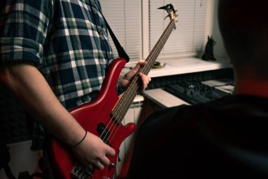 Stüdyoda elektro gitarlı bir rock müzisyeni kendi müzik enstrümanı tellerini çalıyor.