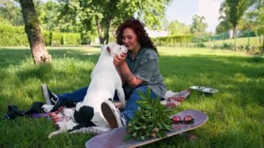 Pitbull cinsinin güzel beyaz köpeği Staffordshire Teriyeri parkta yürürken sahibi köpeği burnundan öpüyor.