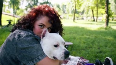 Pitbull 'un güzel beyaz köpeği Styfordshire Teriyeri yazın parkta yürürken sahibinin köpek resmine sarılır.