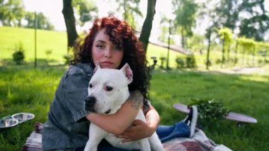 Pitbull 'un güzel beyaz köpeği Styfordshire Teriyeri yazın parkta yürürken sahibinin köpek resmine sarılır.