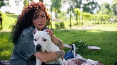 Pitbull 'un güzel beyaz köpeği Styfordshire Teriyeri yazın parkta yürürken sahibinin köpek resmine sarılır.