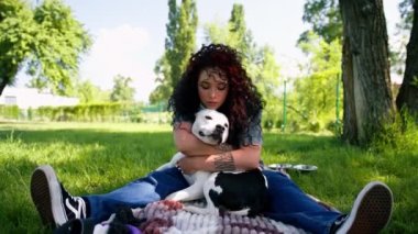 Pitbull 'un güzel beyaz köpeği Styfordshire Teriyeri yazın parkta yürürken sahibinin köpek resmine sarılır.