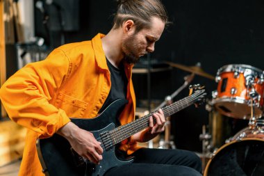 Stüdyoda elektro gitarlı genç bir rock sanatçısının portresi kendi müzik aleti davullarını çalıyor.
