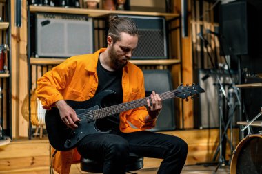 Stüdyoda elektro gitarlı genç bir rock sanatçısının portresi kendi müzik aleti davullarını çalıyor.