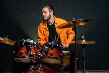 Genç bir erkek davulcu profesyonel bir müzisyenin prova şarkısında bir kayıt stüdyosunda davul çalar.