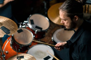 Genç bir erkek davulcu profesyonel bir müzisyenin prova şarkısında bir kayıt stüdyosunda davul çalar.