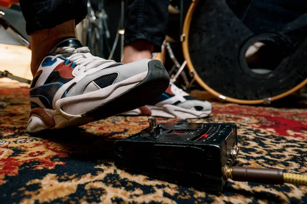 man\'s foot pressing bass drum pedal in recording studio drummer drumming indoors closeup