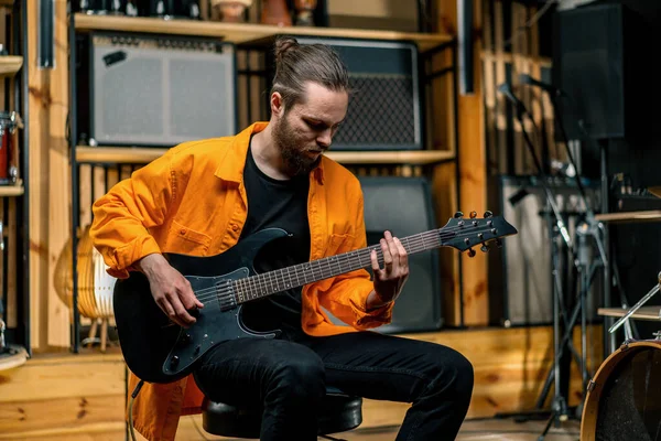 Stüdyoda elektro gitarlı genç bir rock sanatçısının portresi kendi müzik aleti davullarını çalıyor.