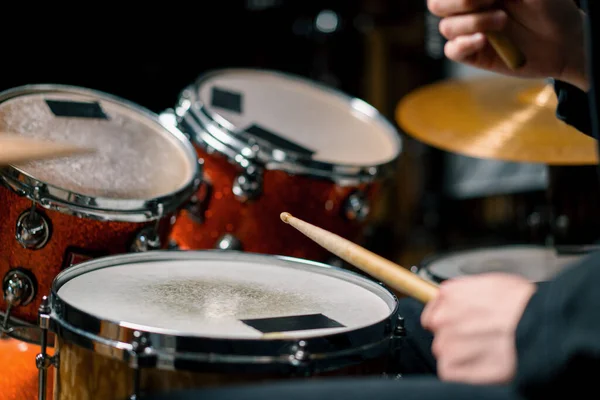 drummer plays a drum kit in a recording studio at a professional musician rehearsal recording a song beats the sticks on the instrument closeup
