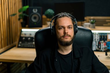 Profesyonel müzik stüdyosunda kulaklık takan genç ciddi ses mühendisinin portresi.