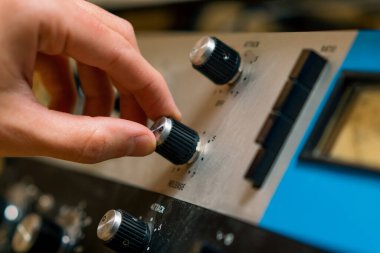 Ses mühendisi dijital ses karıştırıcı sürgüleri kullanıyor. Mühendis tuşlara basıyor. Kontrol paneli ses kayıt stüdyosu teknisyenini kapat.