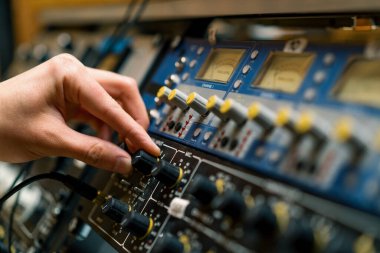 Ses mühendisi dijital ses karıştırıcı sürgüleri kullanıyor. Mühendis tuşlara basıyor. Kontrol paneli ses kayıt stüdyosu teknisyenini kapat.