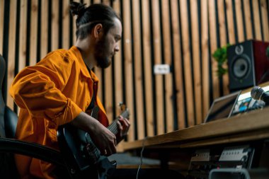 Stüdyoda elektro gitarlı bir rock müzisyeni kendi müzik enstrümanı tellerini çalıyor.