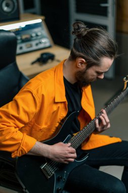 Stüdyoda elektro gitarlı bir rock müzisyeni kendi müzik enstrümanı tellerini çalıyor.