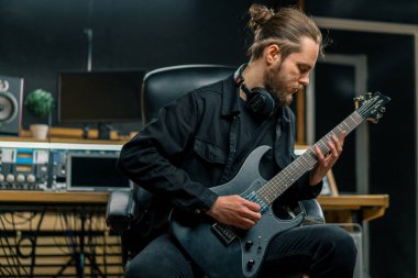 Stüdyoda elektro gitarlı bir rock müzisyeni kendi müzik enstrümanı tellerini çalıyor.