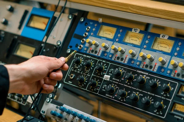 音響エンジニアはコネクターの音楽装置の録音スタジオが付いているオーディオケーブルの専門ワイヤーを接続します — ストック写真
