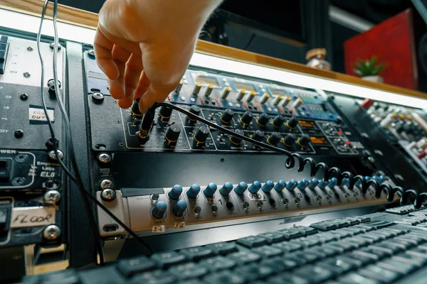 音響エンジニアはコネクターの音楽装置の録音スタジオが付いているオーディオケーブルの専門ワイヤーを接続します — ストック写真
