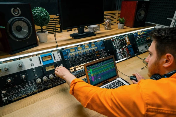 年轻的音效工程师在音乐工作室里与监控器和均衡器混合和掌握录制歌曲音频音轨屏幕的曲目 — 图库照片