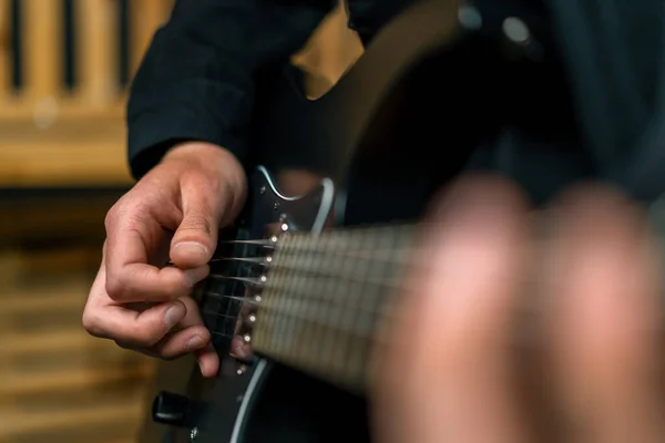 rock performer with electric guitar in recording studio recording playing own track creating song musical instrument strings closeup