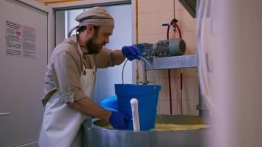 Peynir üreticisi, peynir üretimi için peynirleri kalıplara döküyor.