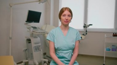 Jinekolog doktor, jinekolog muayenehanesinde, ultrason ve jinekoloji kürsüsünün yanında oturuyor.