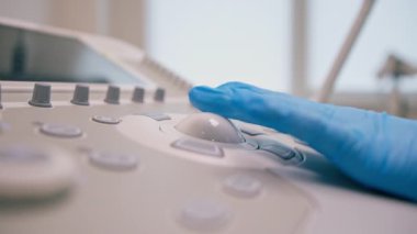 Jinekolog transvajinal ultrason cihazı kullanır düğmelere basar ve klinikte iç organlarının fotoğrafını çeker.
