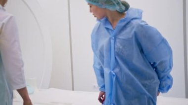 Tıbbi klinikteki bir radyolog cihazı hastanın kafasına, beyin manyetik rezonans görüntüleme prosedüründen önce yerleştiriyor.