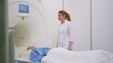 Tıbbi klinikteki profesyonel bir radyolog manyetik rezonans görüntüleme işlemi geçiren bir hastayı izler.
