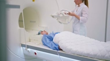 Tıbbi klinikteki bir radyolog cihazı hastanın kafasına, beyin manyetik rezonans görüntüleme prosedüründen önce yerleştiriyor.