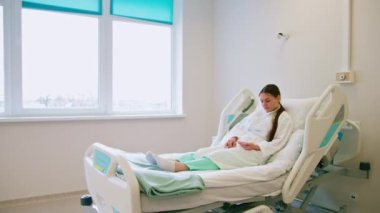Genç hasta kız acil çağrı düğmesine basıyor ve klinikteki hastane koğuşunda hemşire yardımı istiyor.