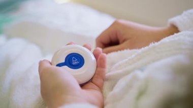 Bir sağlık kliniğinde acil durum düğmesine basan bir parmak. Hastanenin koğuşundaki bir hasta yardım için hemşireyi arar.