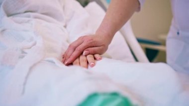 Bir doktorun elleri, hastane odasında bir hastanın elini tutuyor. Bakım ve destek amaçlı.