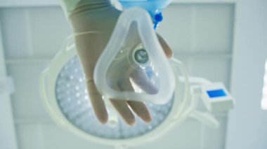 Doktor anestezi uzmanı ameliyat sırasında hastaya anestezi için maske takıyor.