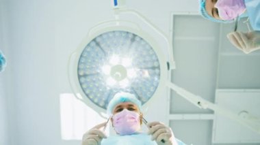 Hastanenin alt katında cerrahi aletler tutan bir grup doktor ve hemşire.