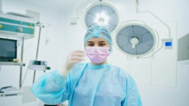 Steril koruyucu giysili genç bir doktorun portresi ameliyattan sonra ameliyathanede maskesini çıkarıyor.